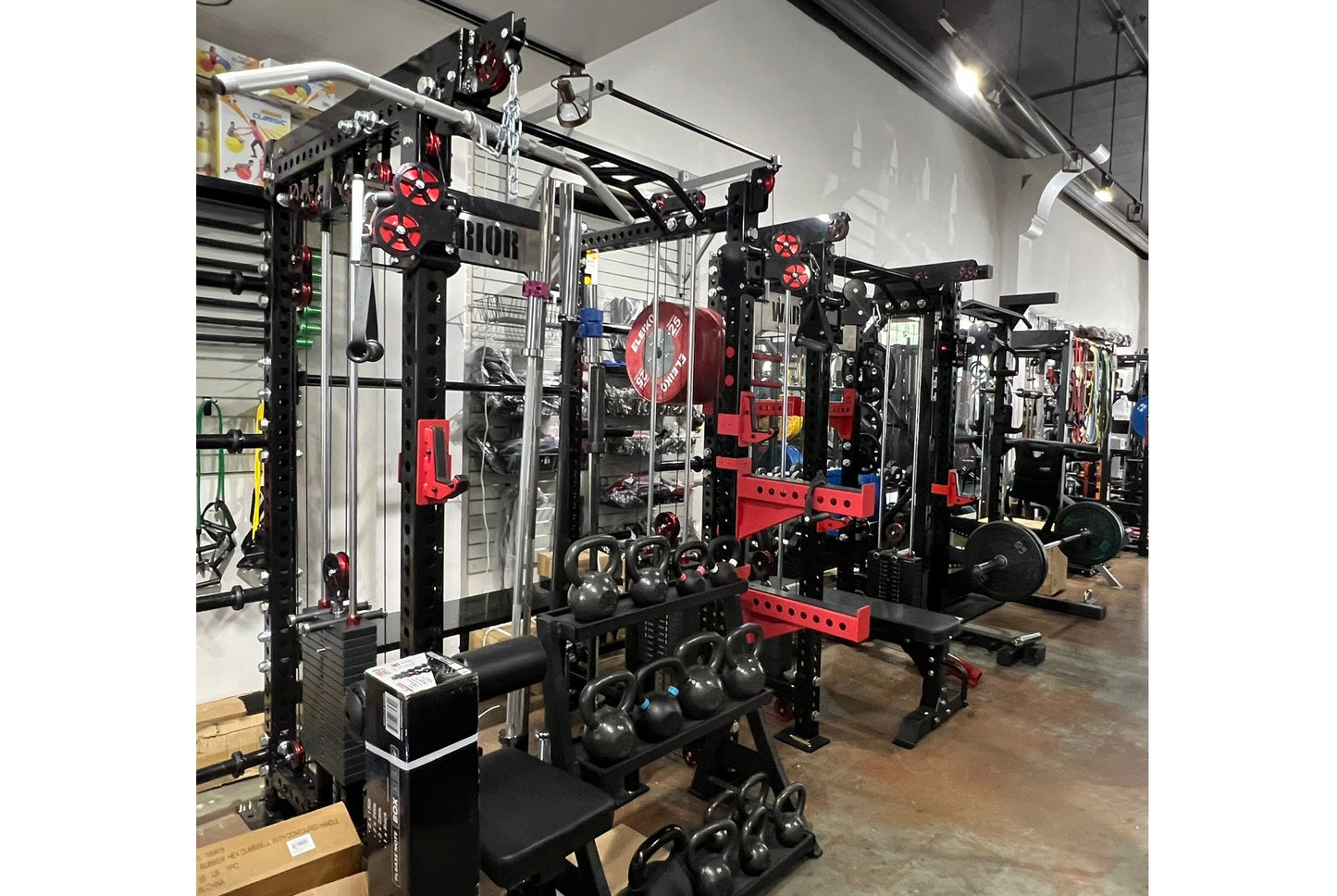 Black and red cable crossover power rack with dual pulleys, lat pulldown attachment, and kettlebell storage in gym setting