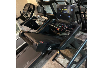 Black folding treadmill with digital display showing speed and incline, dual handholds, and black frame on concrete surface