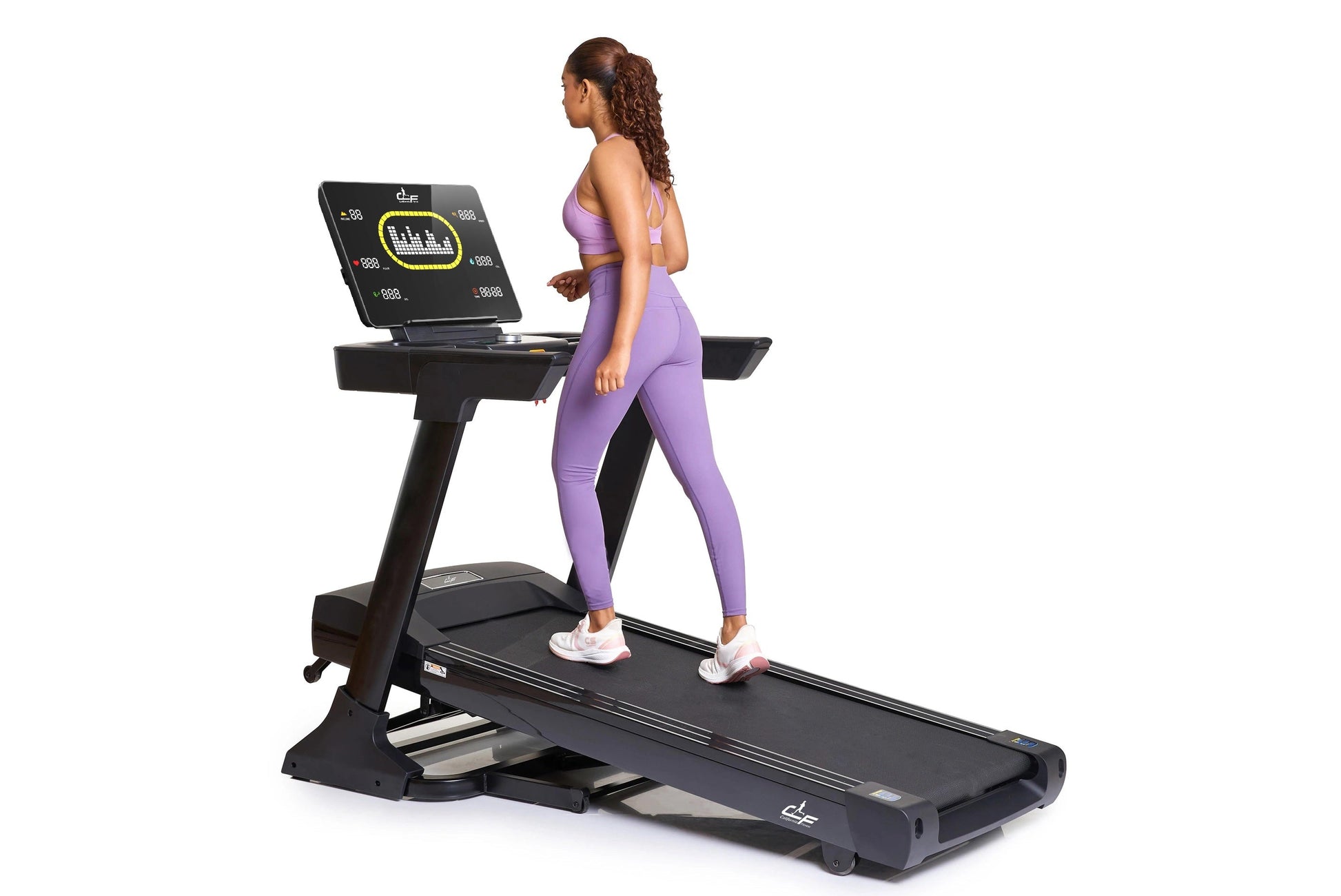 Woman wearing purple sports bra and leggings running on black folding treadmill with digital display screen
