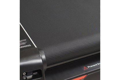 Close-up of black textured treadmill belt and frame showing motor housing and safety warning label