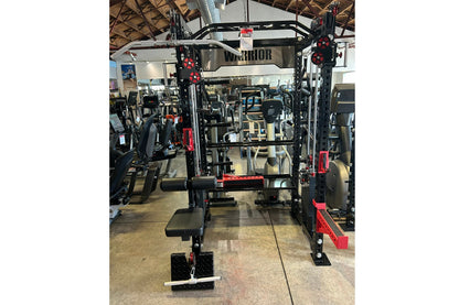 Warrior cable crossover power rack with dual black uprights, red accents, adjustable pulleys, lat pulldown attachment, and we