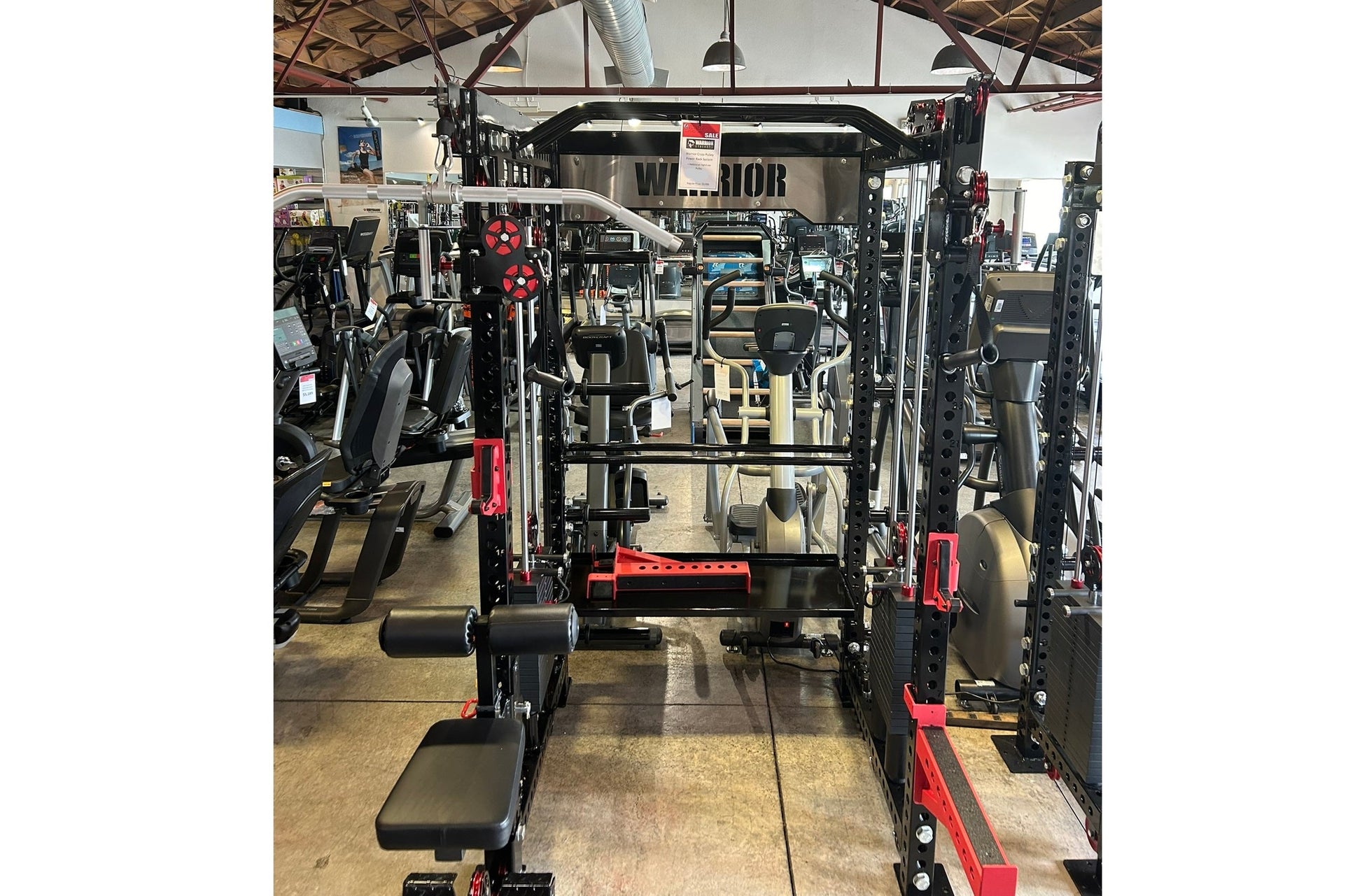 Black and red Warrior cable crossover pulley power rack with lat pulldown attachment in gym facility, front view