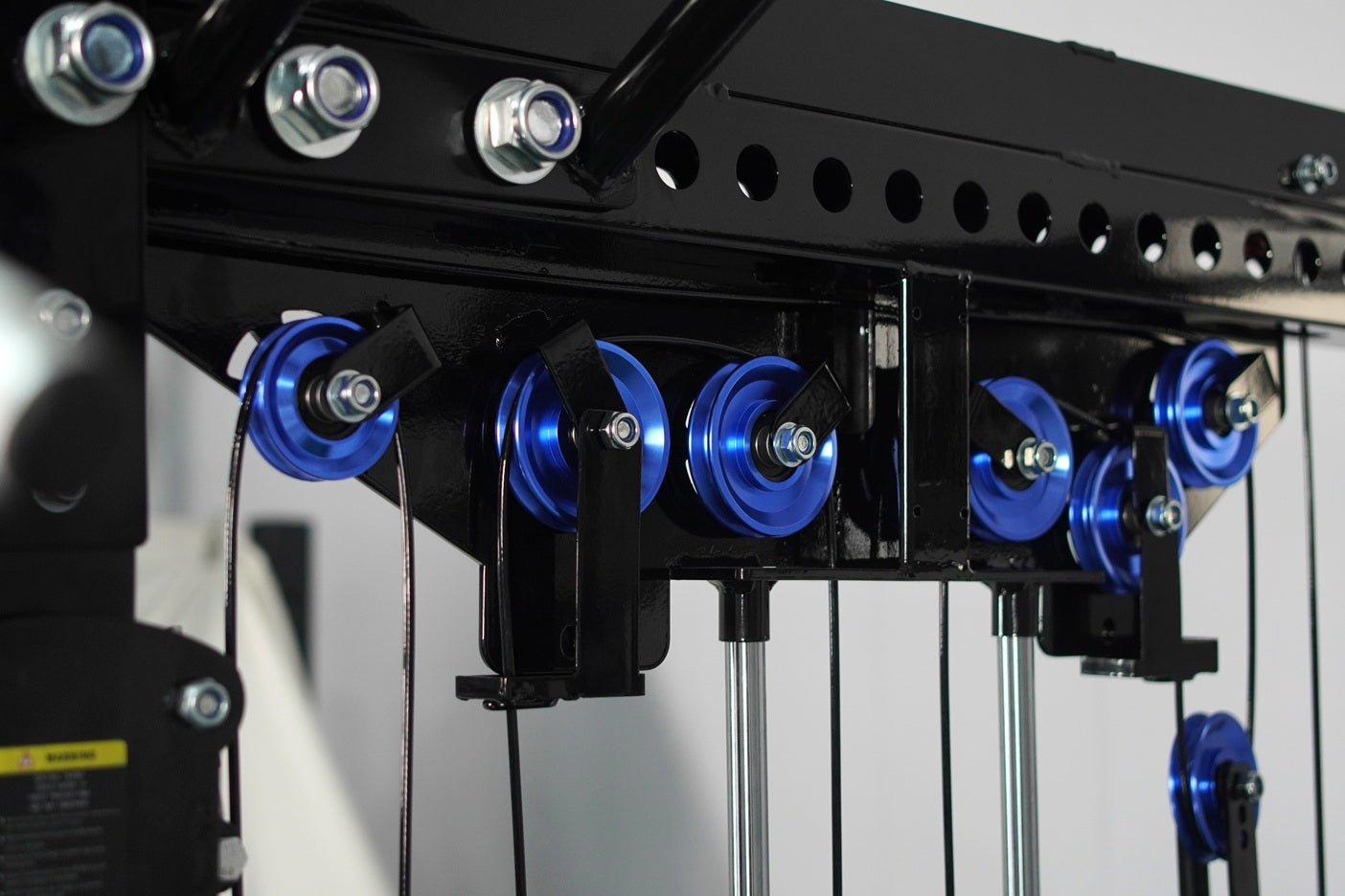 Black cable crossover machine with blue pulleys and metal frame, gym equipment detail view