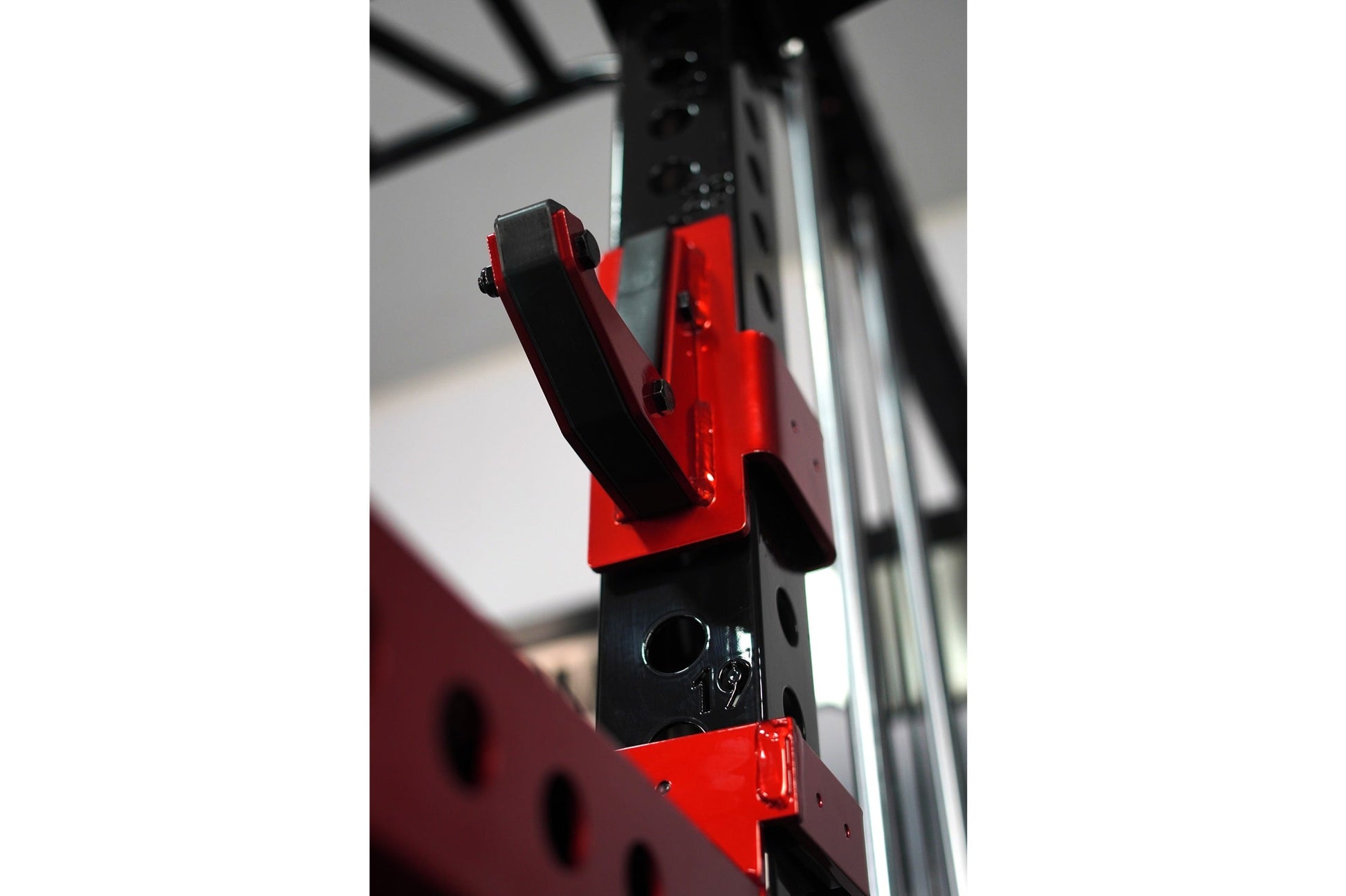 Red and black cable crossover pulley attachment with grip handles on gym power rack frame
