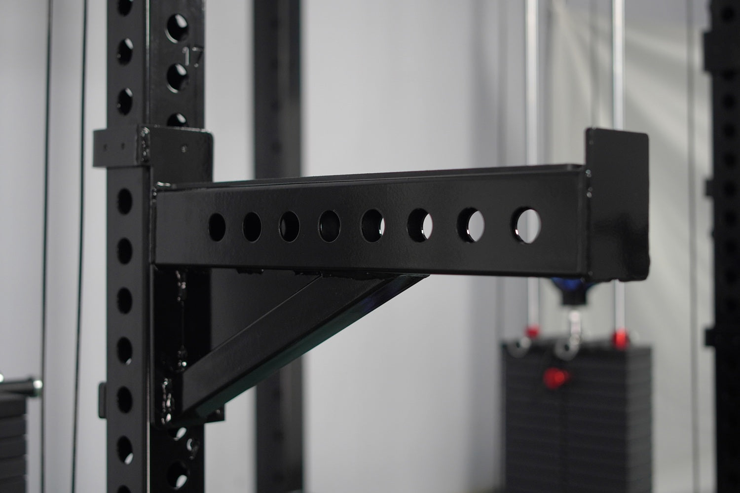 Black steel cable crossover arm with eight circular pulleys attached to vertical rack frame with angled support bracket